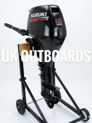 Side profile view of a clean, black 4-stroke Suzuki 9.9hp outboard motor with a long shaft midsection, showing the engine cowlings with silver branding beside its mechanical remote throttle lever box setup.
