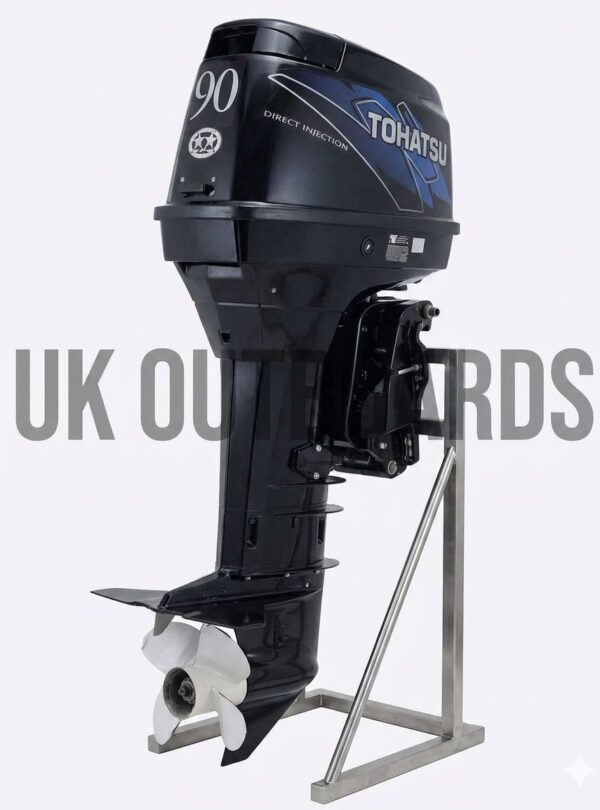 Efficient Tohatsu TLDI Outboard - 2006 90HP MD90B Extra-Long Shaft Marine Unit Three-quarter profile view of an efficient tohatsu tldi outboard motor resting on a wooden service workbench, showcasing its grey top cowling with prominent Tohatsu branding, lower midsection casing with mounting bracket, and extra-long lower unit fitted with a three-blade aluminum propulsion propeller.